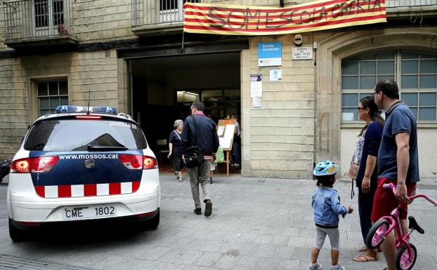 Un coche de los Mossos, frente a un colegio que permanece abierto.