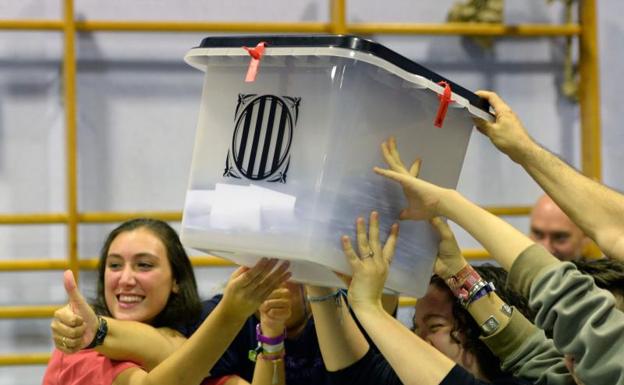 Varios jóvenes sostienen una urna llena de votos.