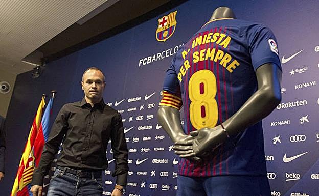 Iniesta, junto a una camiseta conmemorativa de su renovación vitalicia. 