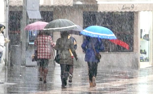 Un grupo de personas camina bajo la lluvia en la Calle Ancha de León capital.