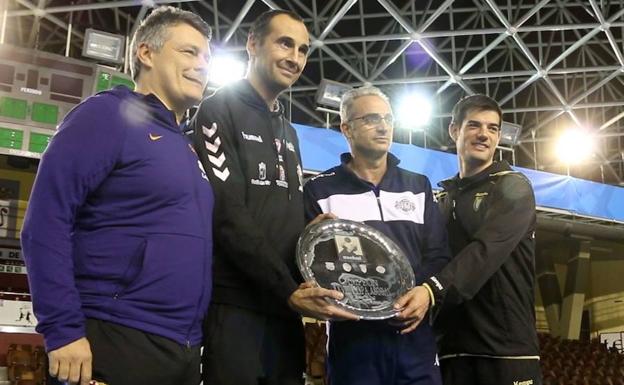 Los entrenadores posan con el trofeo.