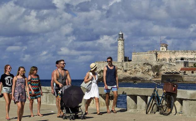 uristas caminan por el Malecón habanero. 