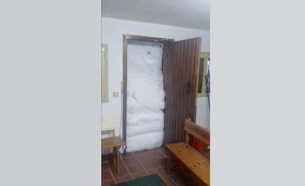 Imagen de una puerta completamente cubierta por la nieve.