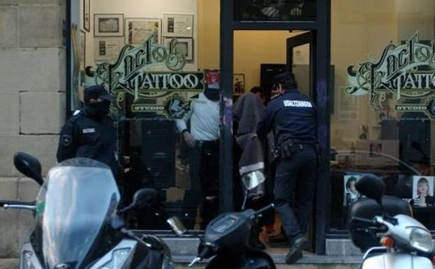 El tatuador es conducido por los agentes tras haber participado en el registro de su local. 