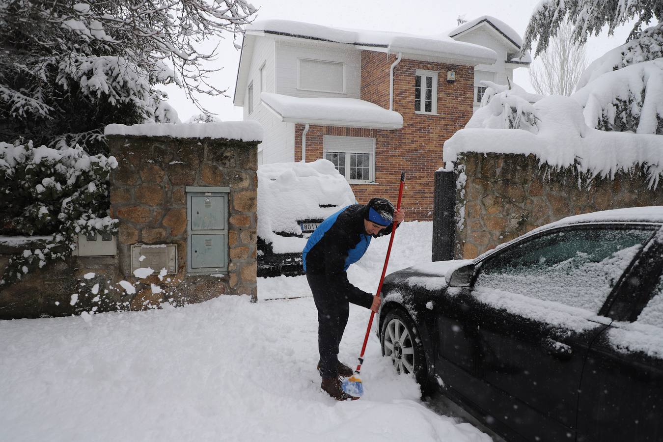 Un vecino de la localidad segoviana de El Espinar limpia la nieve de la entrada de su domicilio bajo una intensa nevada.