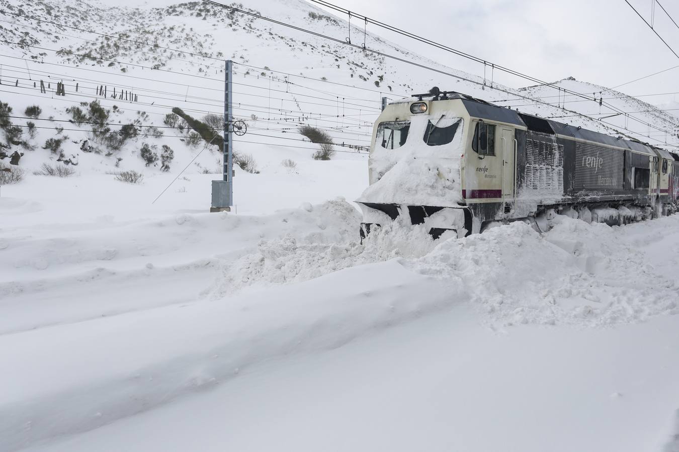 La vía férrea que une León y Asturias, afectada por la nieve. En la imagen, un tren parado en la estación de Busdongo (León).