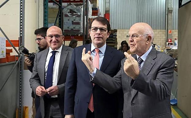 El presidente del PP en Castilla y León, Alfonso Fernández Mañueco, conversa con una voluntaria en su visita el Banco de Alimentos de Valladolid, junto al presidente del PP Valladolid, Jesús Julio Carnero, y el presidente del Banco de Alimentos, Jesús Mediavilla.