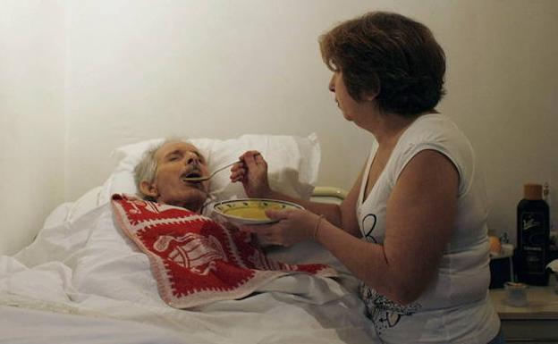 Mujer da de comer a su esposo, enfermo de alzhéimer. 