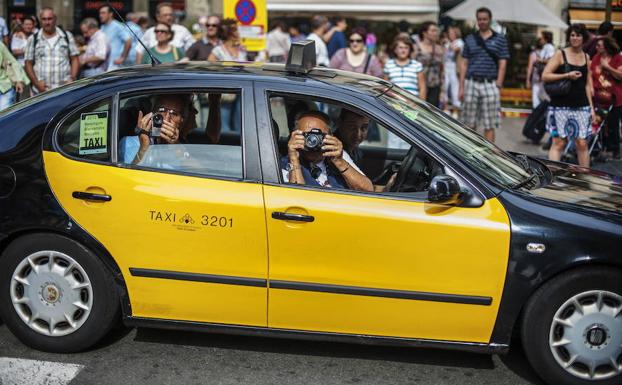 Turistas toman fotografías de Barcelona al paso de su taxi por Las Ramblas. 