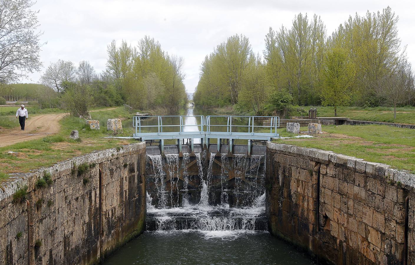 El agua cae por las compuertas superiores de la esclusa sexta del Canal de Castilla en Herrera de Pisuerga (Palencia).