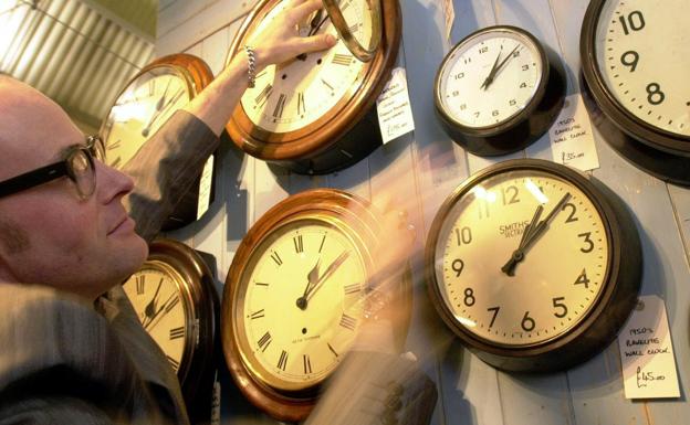 Un restaurador cambia de hora los relojes de su tienda de Londres.