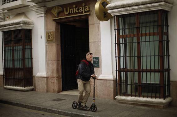 Un transeúnte pasa junto a una sucursal de Unicaja.