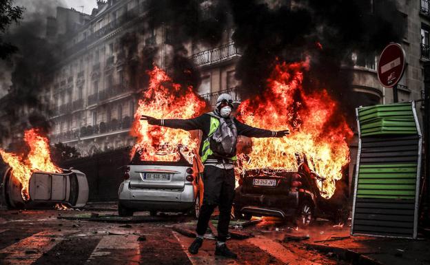 Un manifestante con un chaleco amarillo protesta por los precios del carburante junto a varios coches en llamas, en París, Francia, el 1 de diciembre del 2018. 