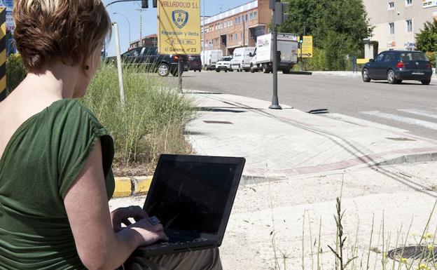 Una mujer usa wifi para conectarse a internet con su portátil en la calle.