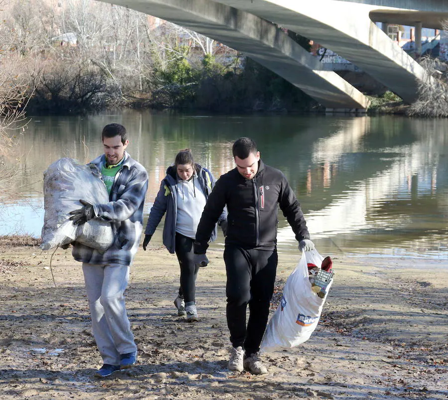 Unos voluntarios recogen basura en las márgenes del río Pisuerga a su paso por Valladolid.