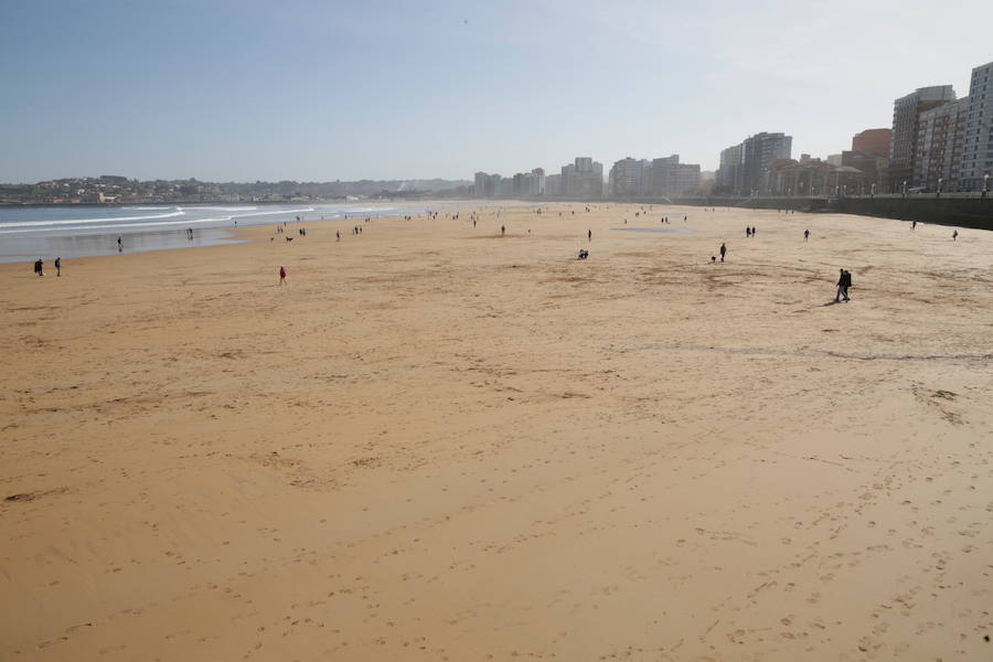 Decenas de personas se animaron a pasear por la Playa de San Lorenzo, bajo el sol y por la gran extensión de arena que dejó la bajamar