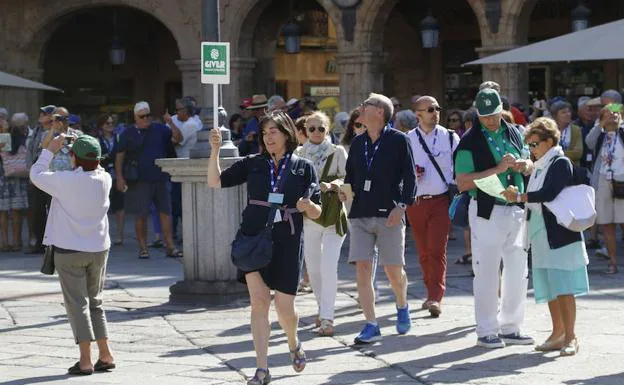 Una mujer guía a un grupo de turistas en Salamanca.
