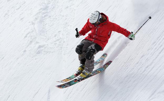 Un esquiador descendiendo por una pista de esquí.