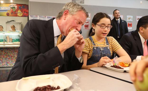 Bill de Blasio come en una escuela. 