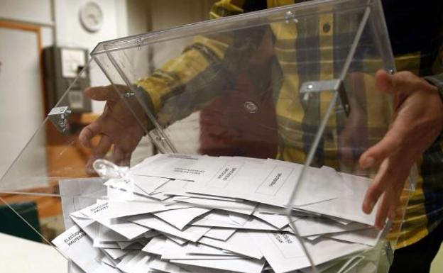 Un hombre vacía una urna antes de proceder al recuento de los votos