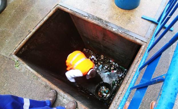 Uno de los trabajadores de FCC recoge la basura en el interior de un contenedor subterráneo en la plaza de la Encina de Ponferrada.