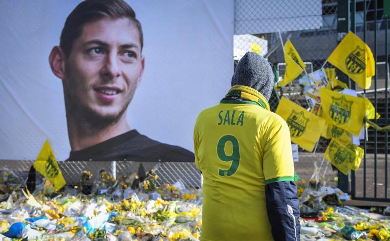 Un aficionado pasa junto a un retrato rodeado de flores en recuerdo de Emiliano Sala. 