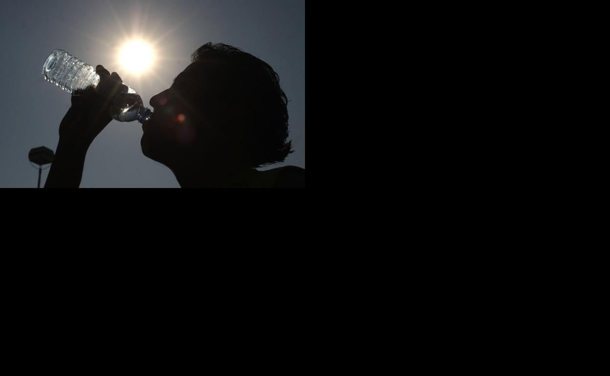 Un joven se refresca con una botella de agua.