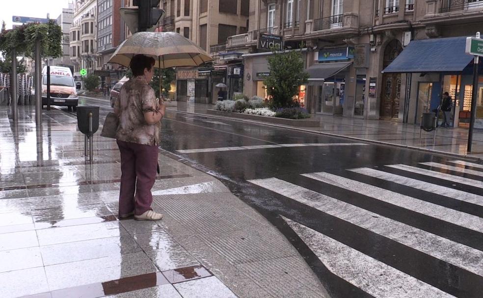 Un mujer se protege de la lluvia en León.