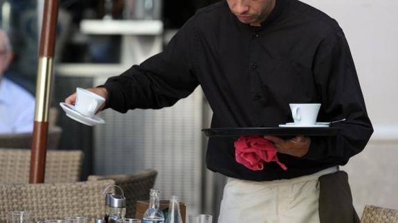 Un camarero sirve unos cafés.