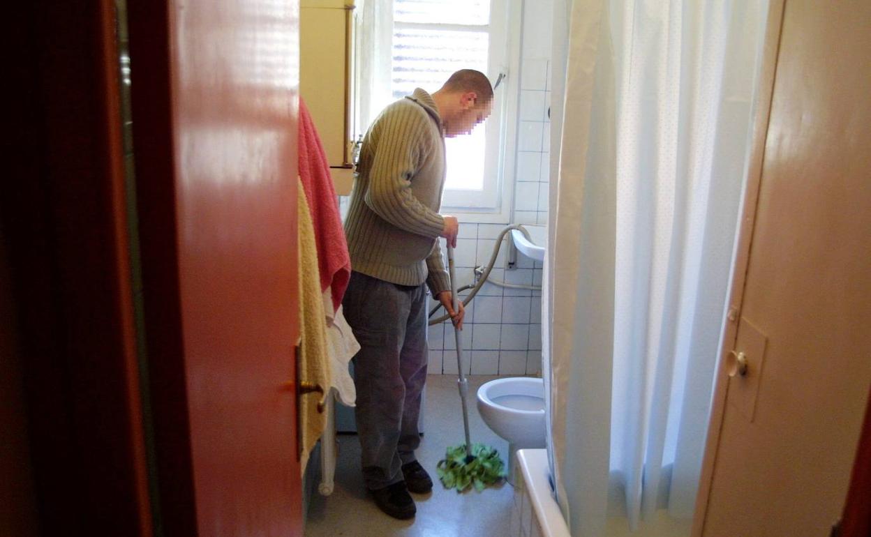 Un hombre que vive solo limpia el cuarto de baño de su casa.