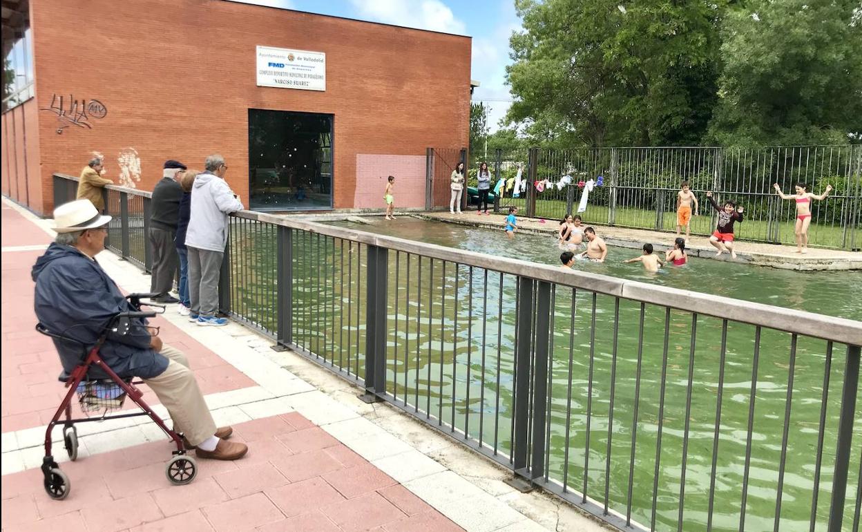 Personas mayores observan a un grupo de escolares que se dan un chapuzón en el club de piragüismo.