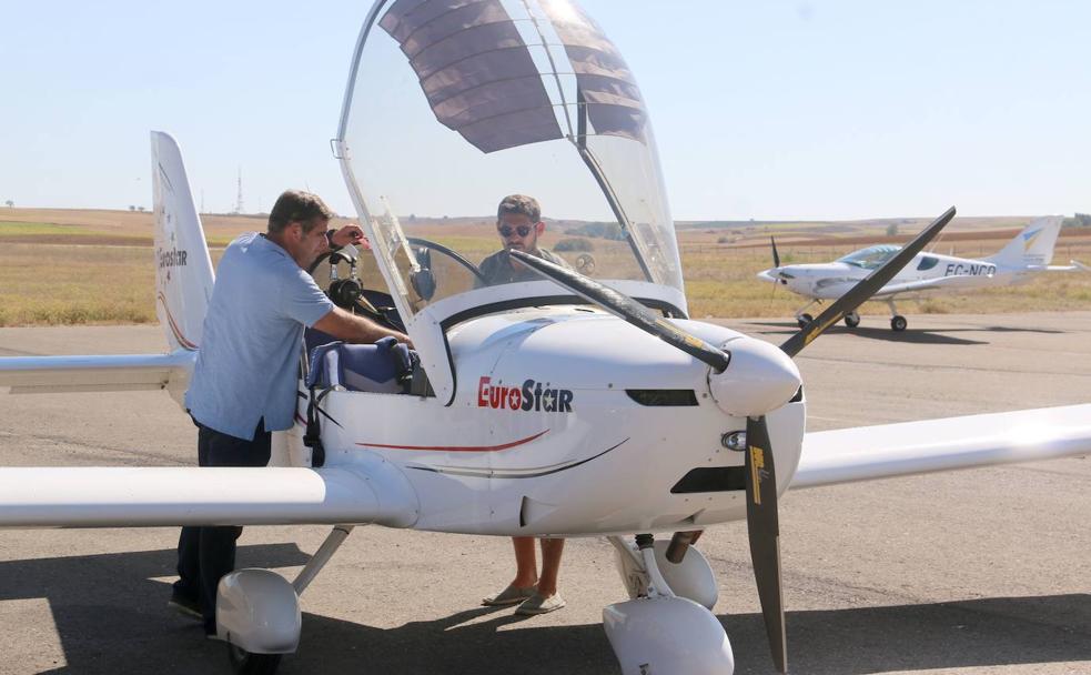 Un piloto empuja su avión en el aeródromo.