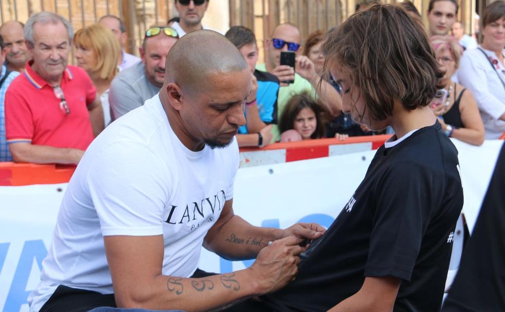 Roberto Carlos firma la camiseta a una niña.