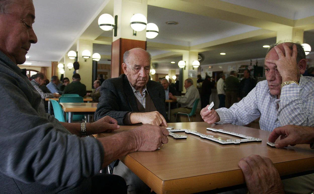 Un grupo de jubilados juega al dominó en una cafetería.