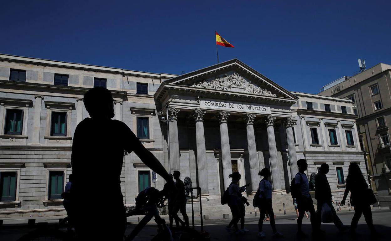 Un grupo de personas pasea por delante del Congreso de los Diputados. 