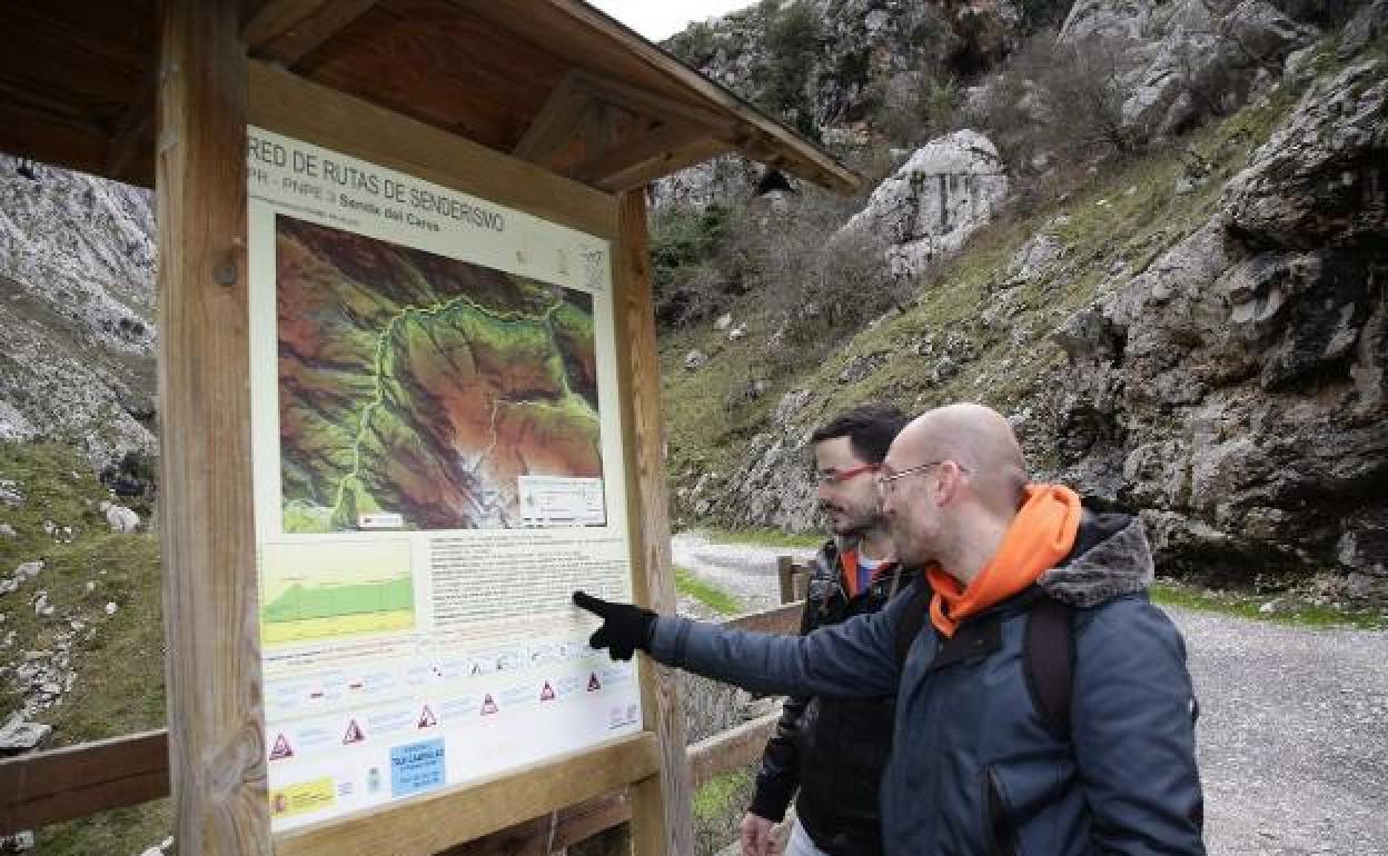 Excursionistas ante un cartel del Parque Nacional en la ruta del Cares, que une Asturias y León.