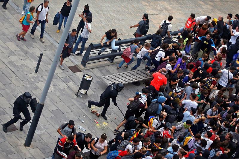 Miembros de los Mossos d'Esquadra cargan contra los centenares de personas que se agolpan ante el Aeropuerto del Prat 