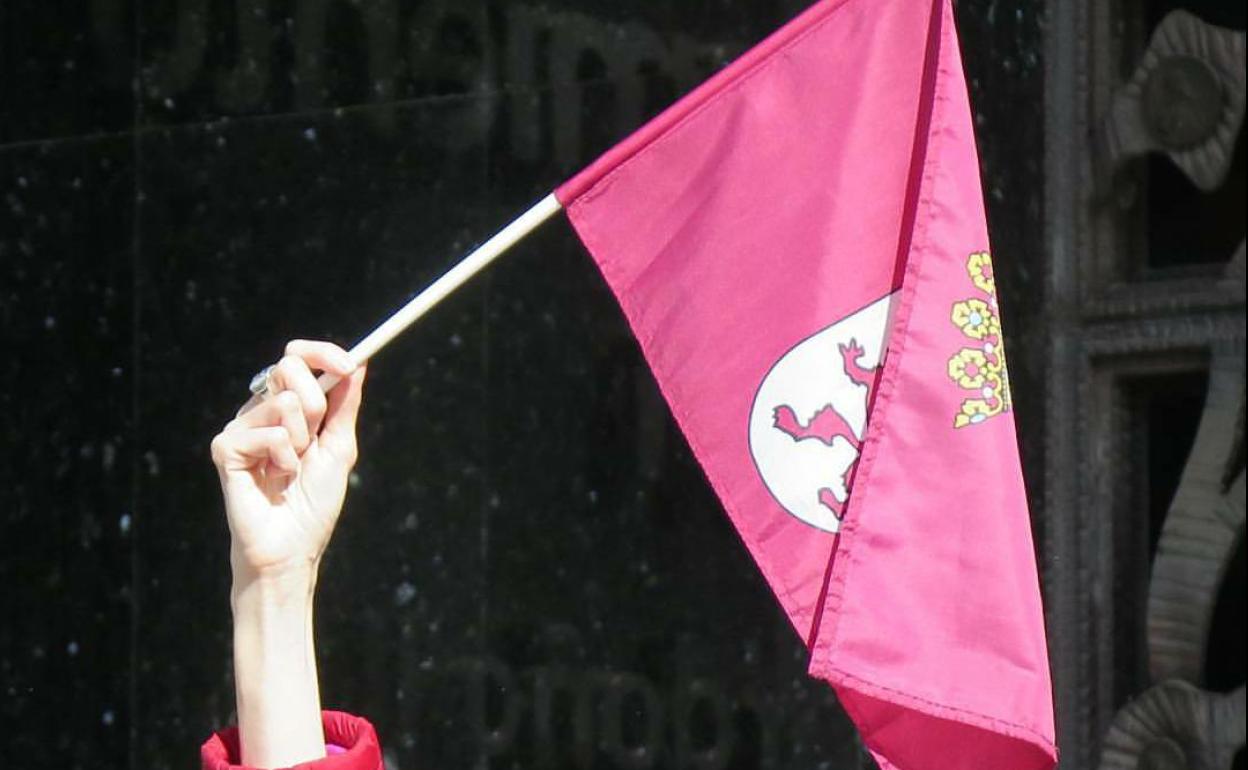 Una mano sostiene una bandera de León. 