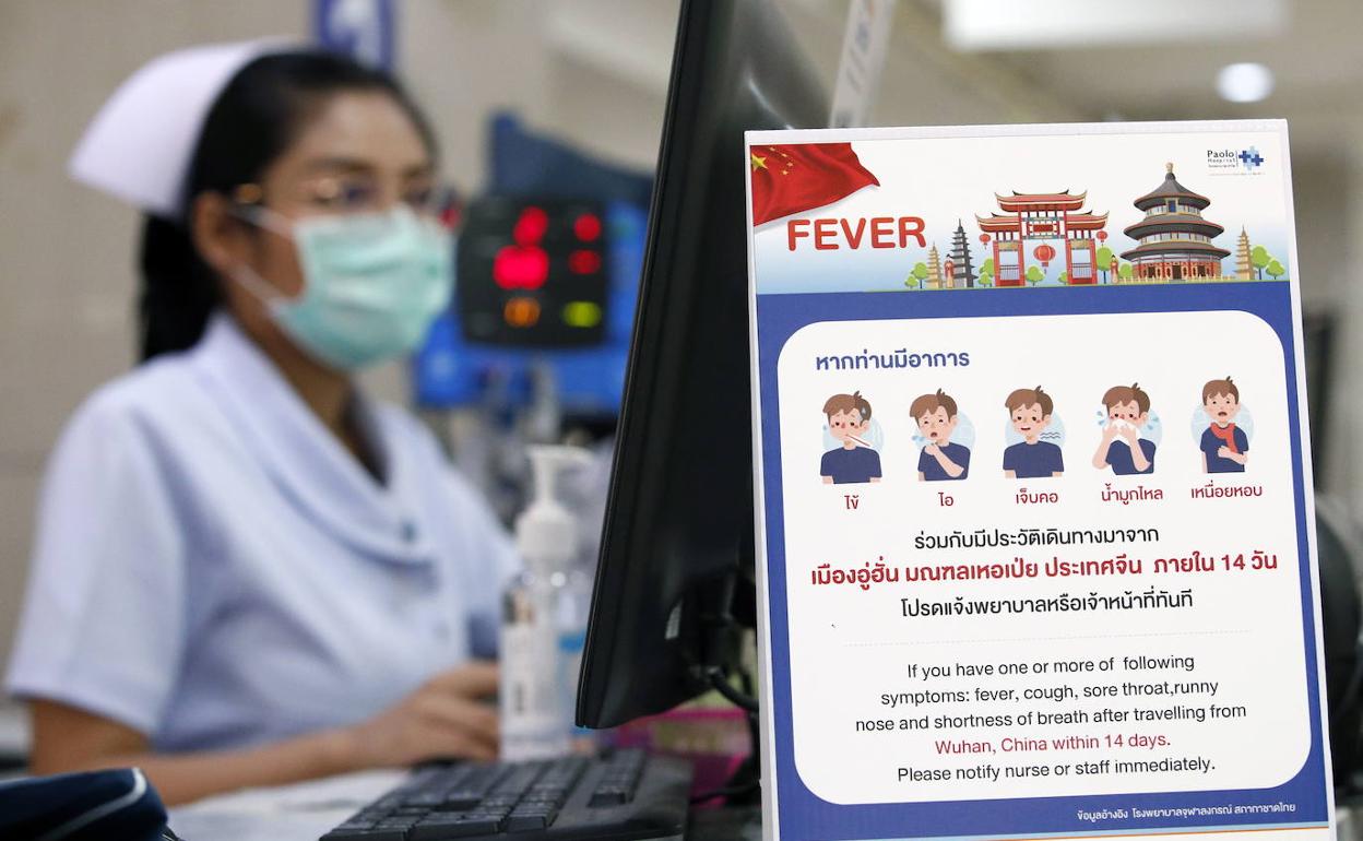 Una enfermera trabaja junto a un cartel de campaña que alerta sobre el coronavirus en un hospital de Bangkok, Tailandia.