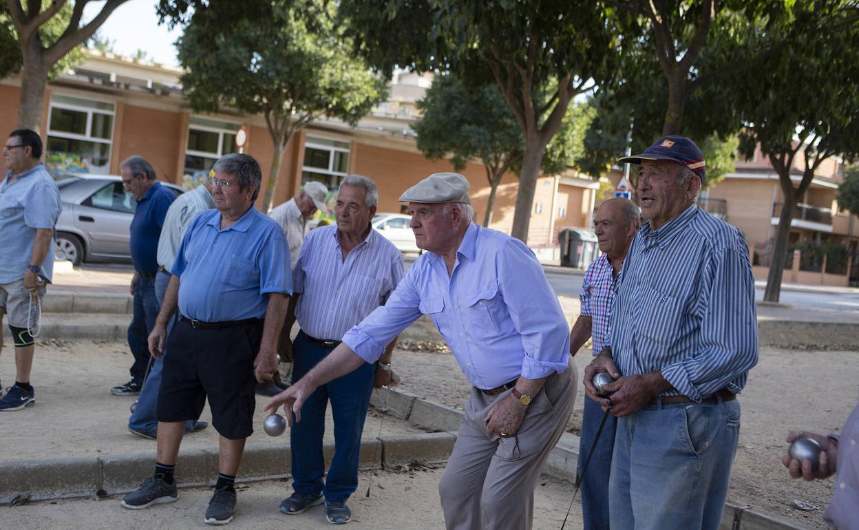 Un grupo de jubilados juega a la petanca en un parque.