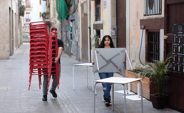 Trabajadores de un bar retiran una terraza tras ordenarse el cierre de espacios públicos en Valencia 