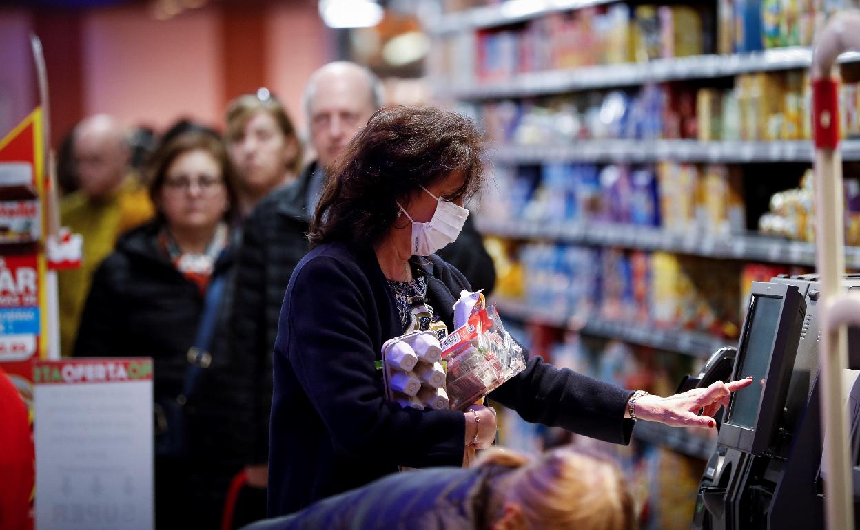 Varias personas hacen la compra en un supermercado.