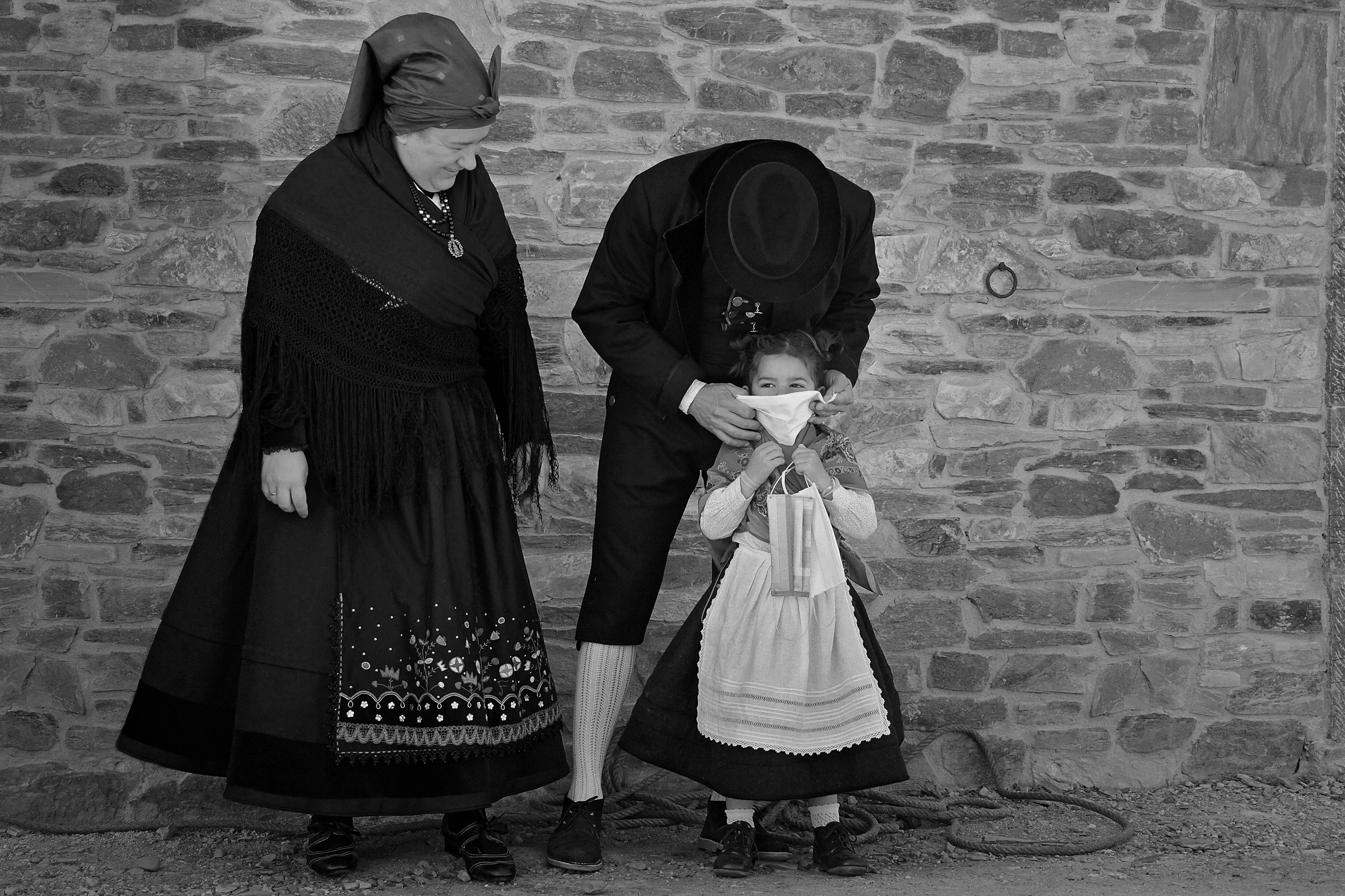 Un matrimonio y su hija, vestidos con indumentaria tradicional leonesa, se protegen contra la infección del coronavirus en Carrizo.
