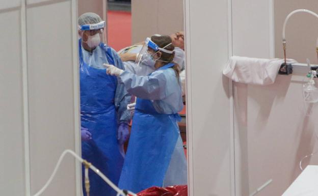 Dos sanitarios protegidos trabajan en el interior del Hospital temporal de Ifema. 