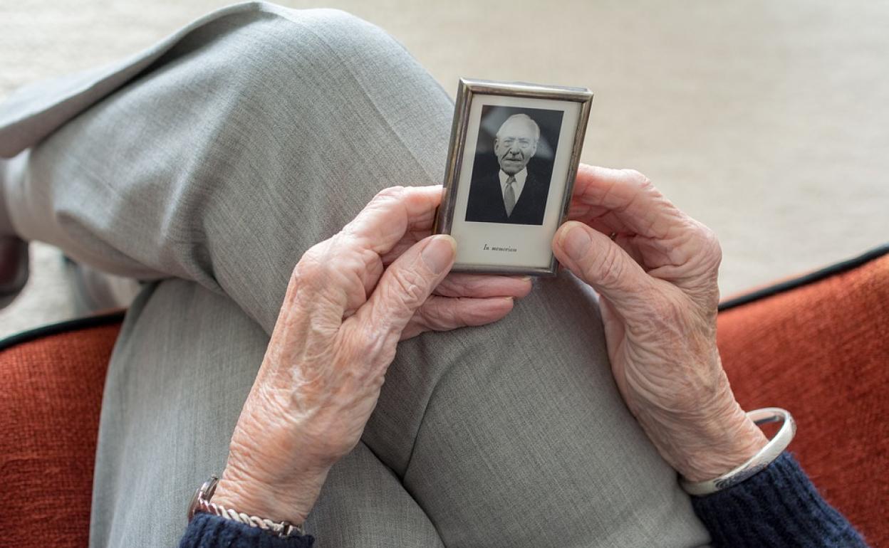 Una anciana contempla la imagen de un familiar.