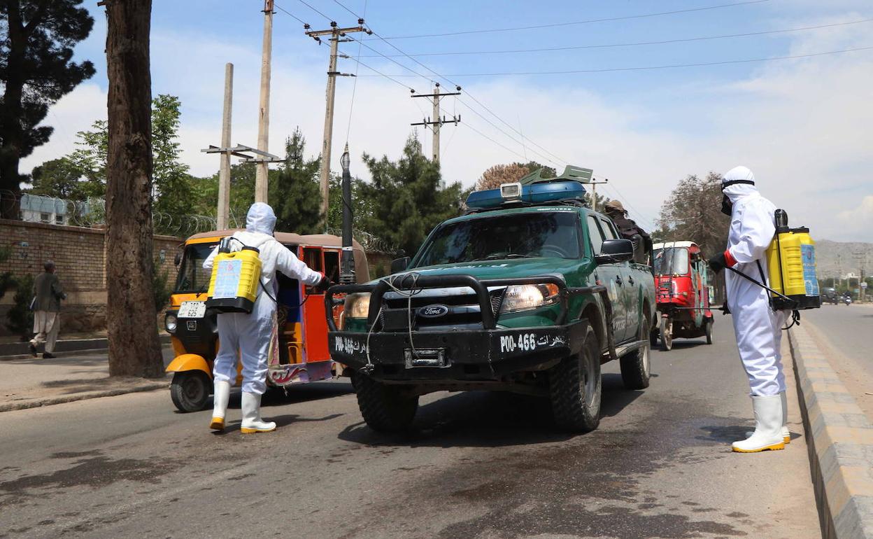 Dos operarios desinfectan vehículos en Herat (Afganistán).