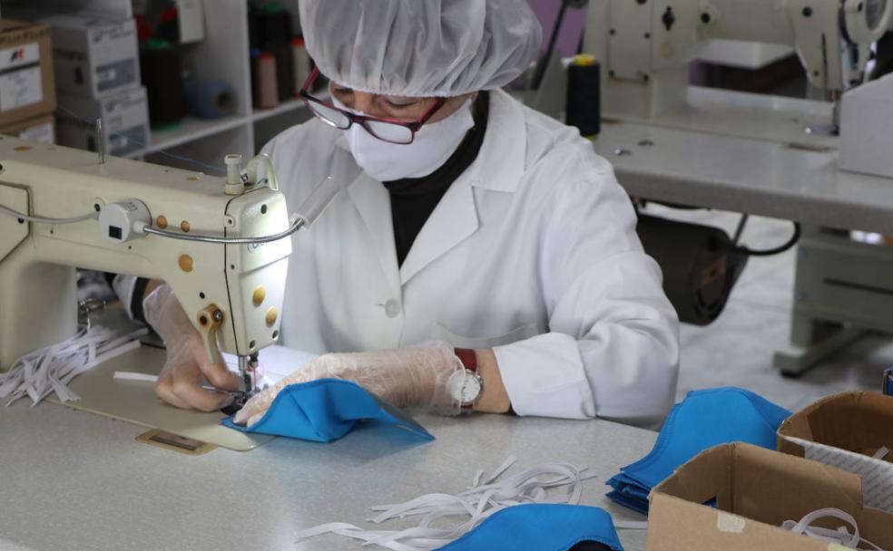 Una de las trabajadoras realiza la costura de las gomas en una mascarilla. 