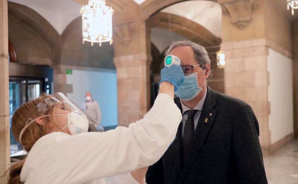 Un miembro de los servicios médicos toma la temperatura al president Quim Torra 