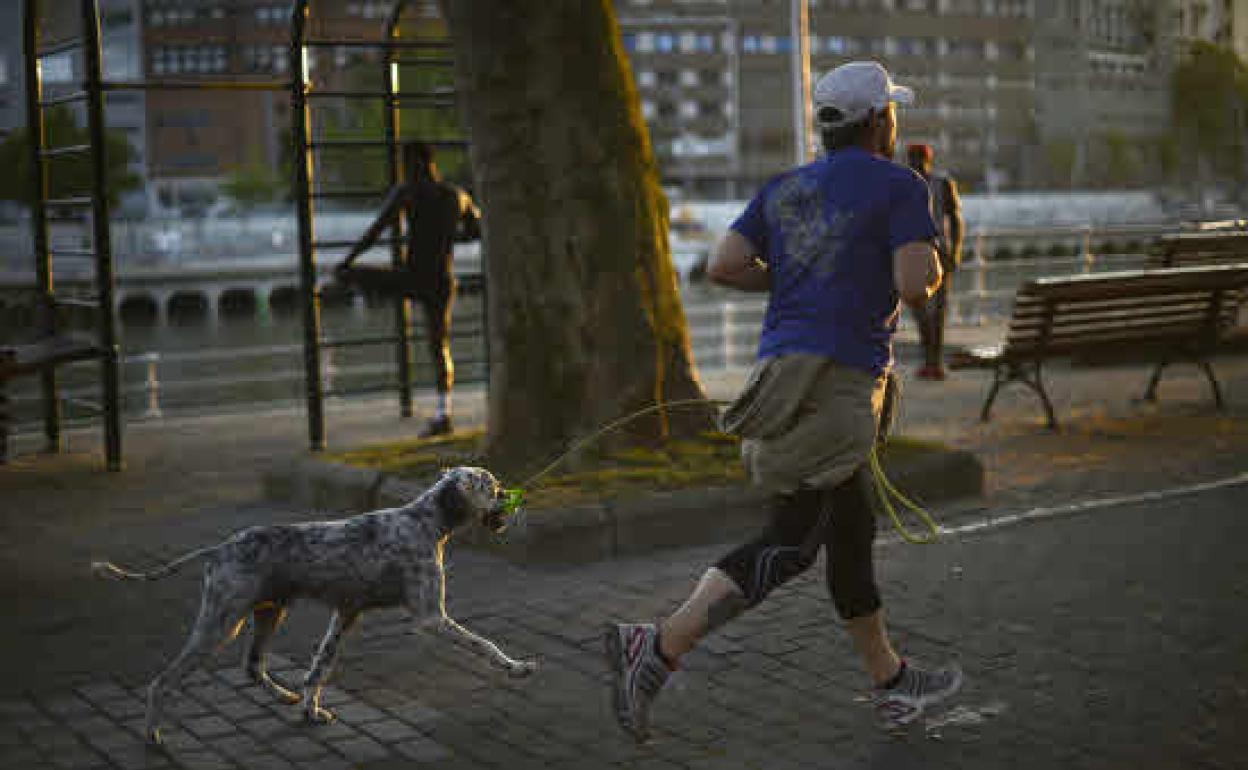 Una persona corre junto a su perro en Bilbao. 