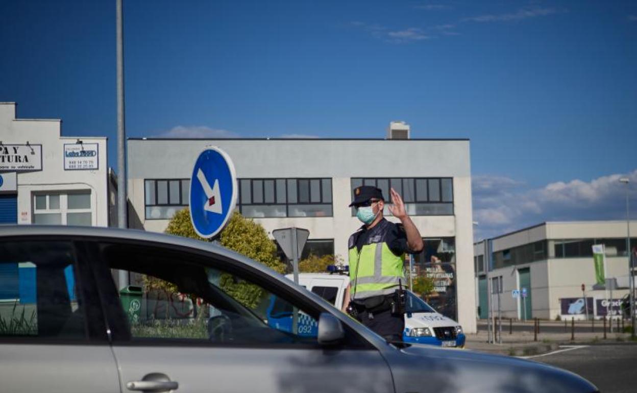 Un Policía Nacional regula la entrada de vehículos durante un control de movilidad 